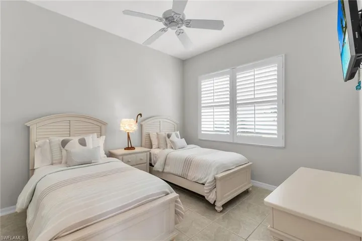 Bedroom with light tile patterned floors, ceiling fan, and baseboards