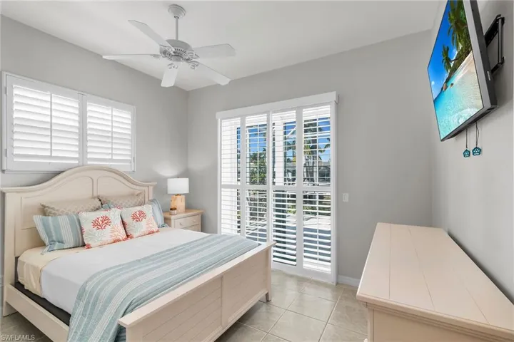 Bedroom with light tile patterned floors, baseboards, access to exterior, and a ceiling fan