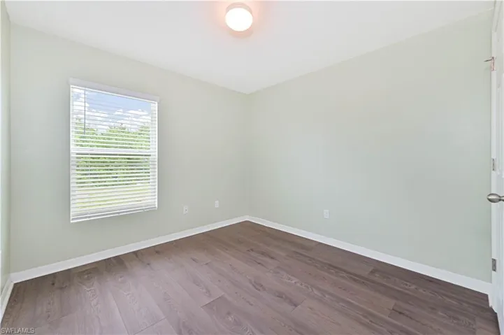 Unfurnished room featuring dark wood-style flooring and baseboards