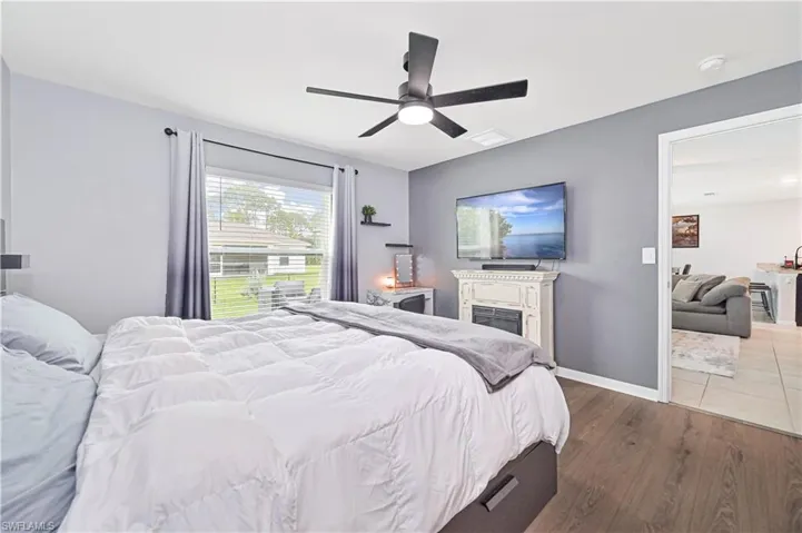 Bedroom with wood finished floors, a fireplace, and a ceiling fan