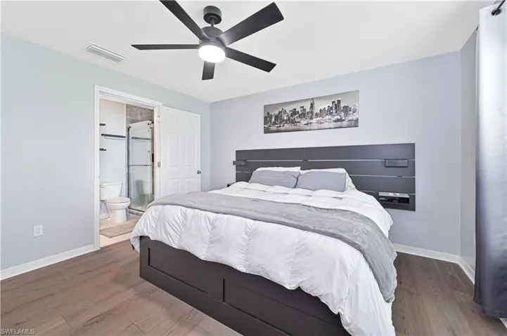 Bedroom with wood finished floors, connected bathroom, and ceiling fan