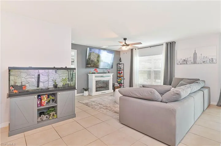 Living area with a fireplace, a ceiling fan, and light tile patterned floors