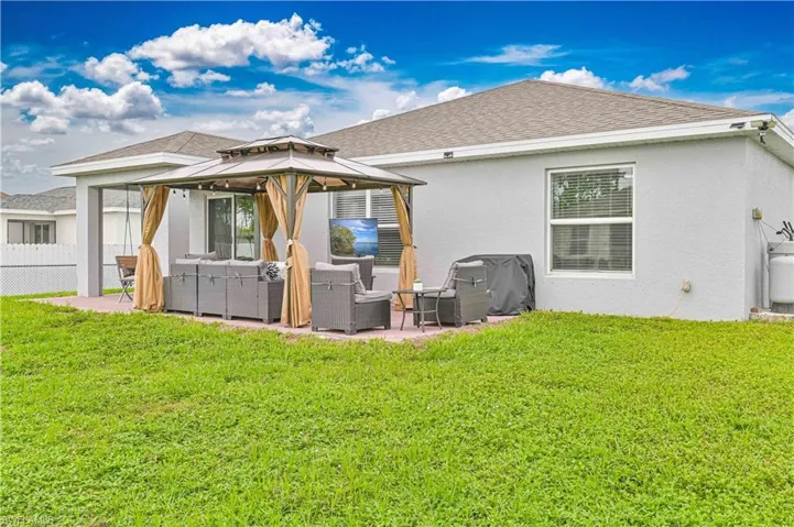Back of house with an outdoor living space, a gazebo, a patio area, stucco siding, and a shingled roof