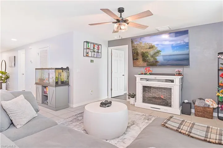 Tiled living room with a ceiling fan and recessed lighting