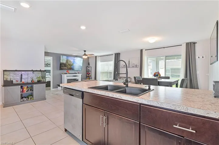 Kitchen with dishwasher, ceiling fan, light countertops, and dark brown cabinetry