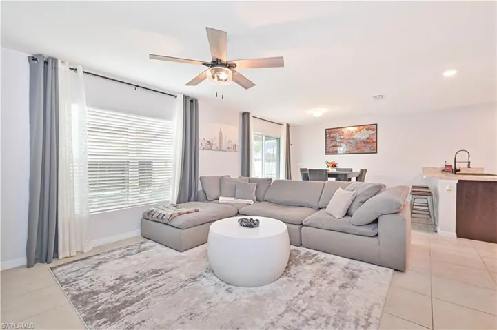 Living area featuring light tile patterned flooring and a ceiling fan