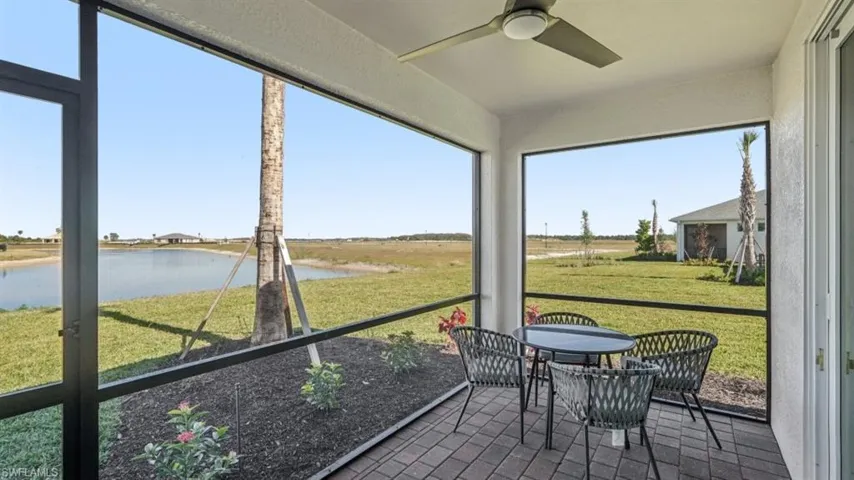 Screened patio with paver flooring, overhead ceiling fan, and landscaped planting beds