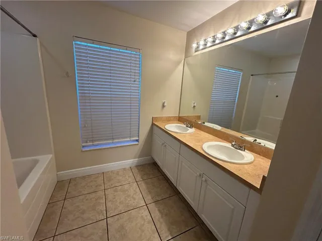 Full bathroom with double vanity and light tile patterned floors