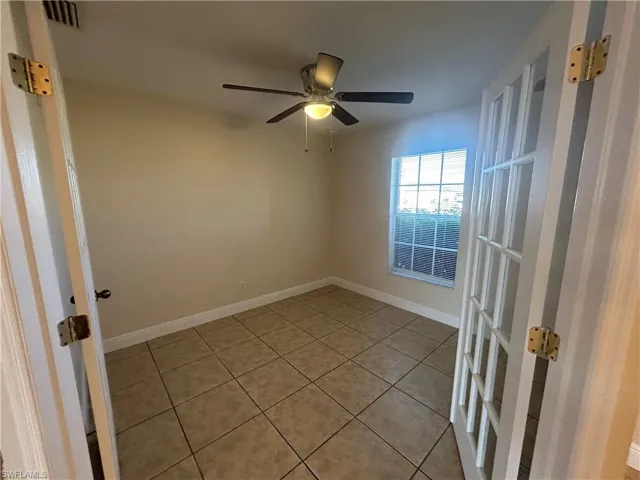 Empty room featuring light tile patterned floors, french doors, and ceiling fan