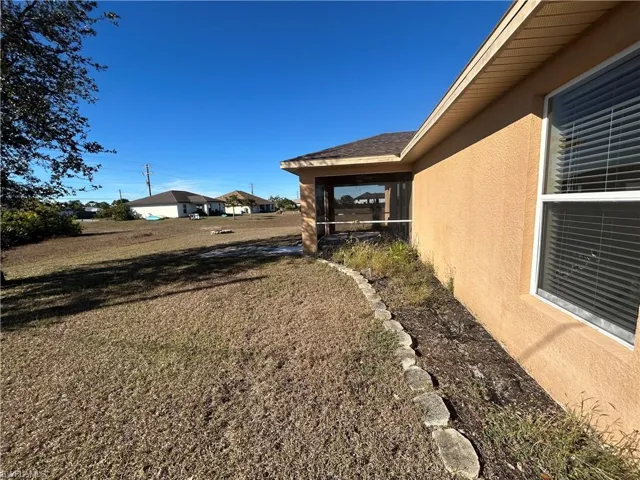View of grassy yard featuring a sunroom