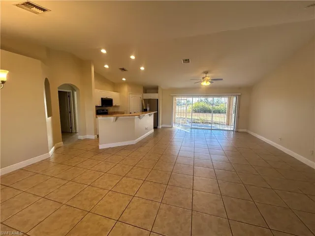 Unfurnished living room featuring vaulted ceiling, light tile patterned floors, recessed lighting, arched walkways, and ceiling fan