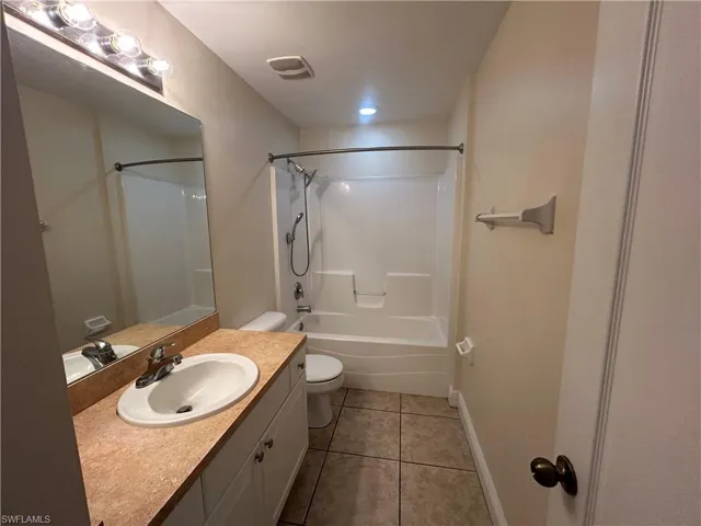 Full bath with vanity, light tile patterned floors, and shower / bath combination