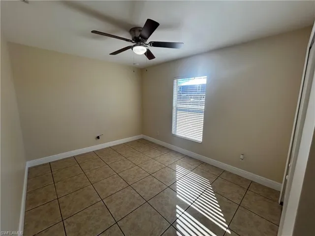 Empty room with light tile patterned floors and a ceiling fan