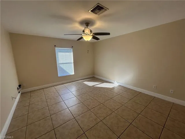 Empty room featuring light tile patterned flooring and ceiling fan
