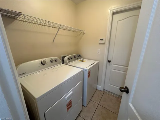 Washroom with light tile patterned floors and separate washer and dryer