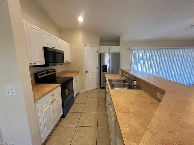 Kitchen with appliances with stainless steel finishes, white cabinets, light countertops, light tile patterned floors, and recessed lighting