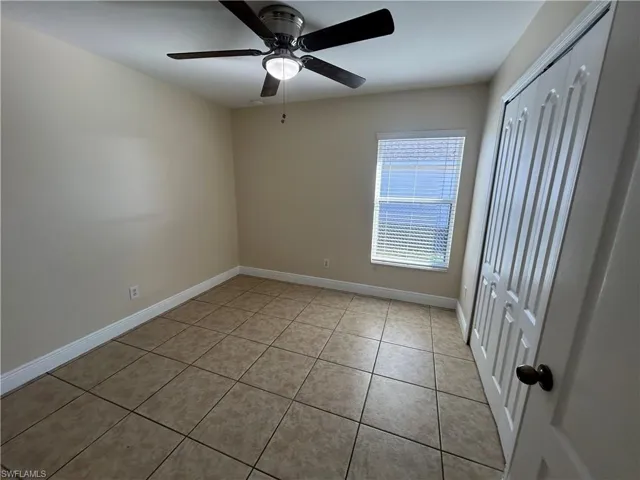 Unfurnished bedroom featuring a closet, light tile patterned flooring, and a ceiling fan