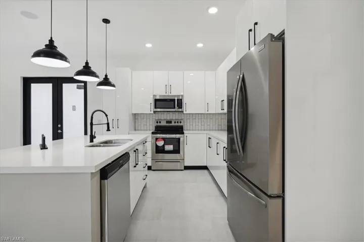 Kitchen with stainless steel appliances, white cabinetry, decorative backsplash, light countertops, and recessed lighting