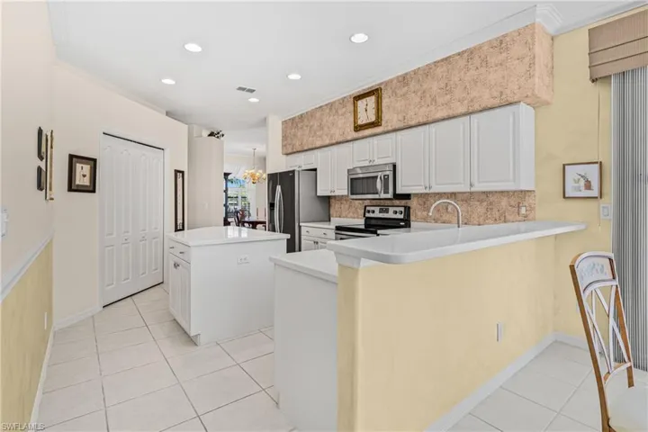 Kitchen featuring white cabinetry, stainless steel appliances, a breakfast bar, recessed lighting, and tile flooring