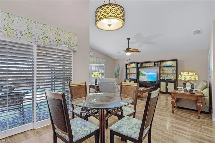 Dining area featuring ceiling fan, light hardwood / wood-style floors, and vaulted ceiling