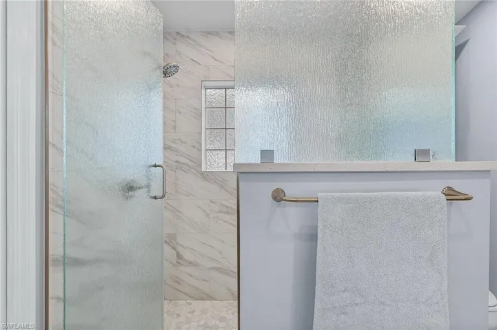 Bathroom featuring a shower with door and toilet