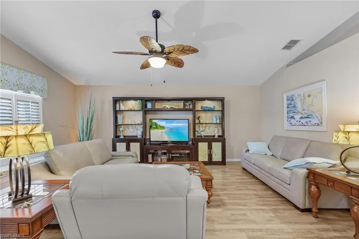 Living room with ceiling fan, light hardwood / wood-style flooring, and vaulted ceiling