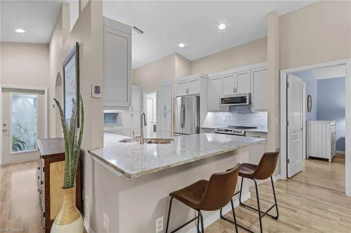 Kitchen featuring a kitchen breakfast bar, sink, light wood-type flooring, kitchen peninsula, and stainless steel appliances