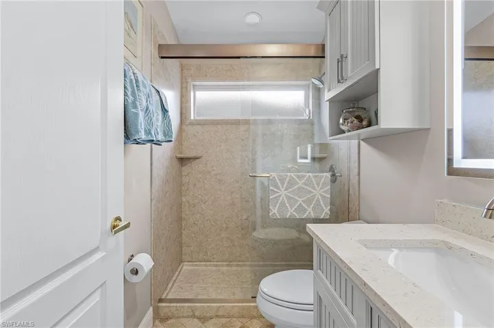 Bathroom with tiled shower, tile patterned floors, vanity, and toilet