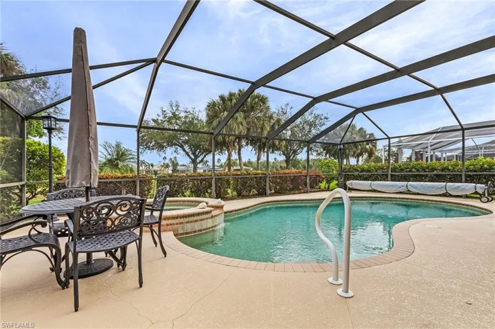View of pool featuring glass enclosure, an in ground hot tub, and a patio