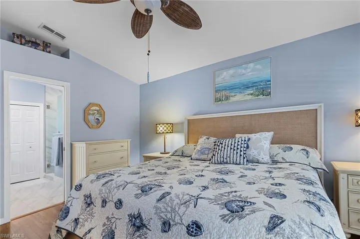 Bedroom with ensuite bathroom, light hardwood / wood-style flooring, ceiling fan, and lofted ceiling