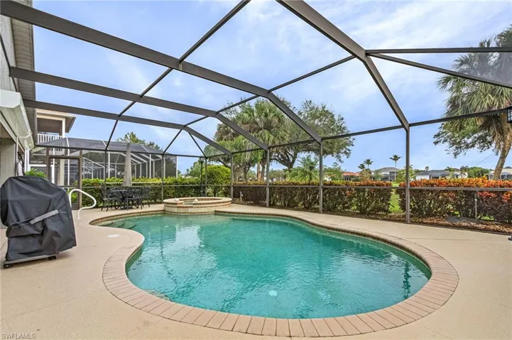 View of swimming pool featuring glass enclosure, area for grilling, a patio area, and an in ground hot tub