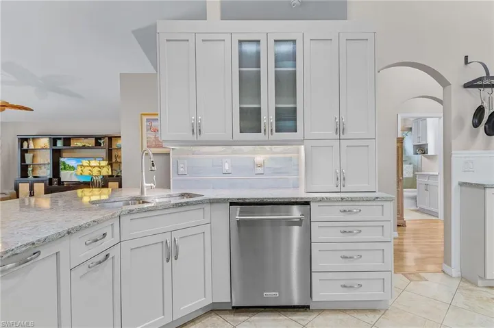 Kitchen with light tile patterned floors, white cabinetry, stainless steel dishwasher, and sink