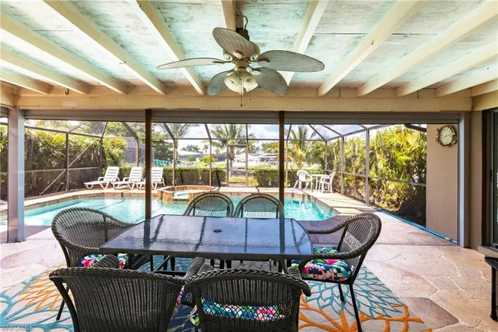 View of patio / terrace featuring glass enclosure, a ceiling fan, outdoor dining area, and a pool with connected hot tub