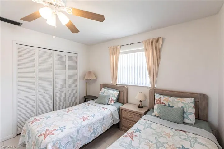 Bedroom with a closet, light tile patterned floors, and a ceiling fan