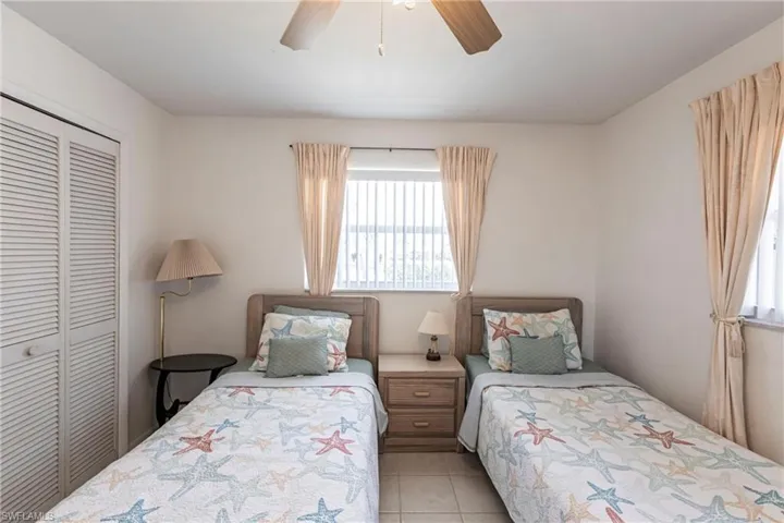 Bedroom with multiple windows, a closet, light tile patterned floors, and ceiling fan