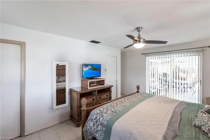 Bedroom with light tile patterned floors, a ceiling fan, and access to lanai & pool area
