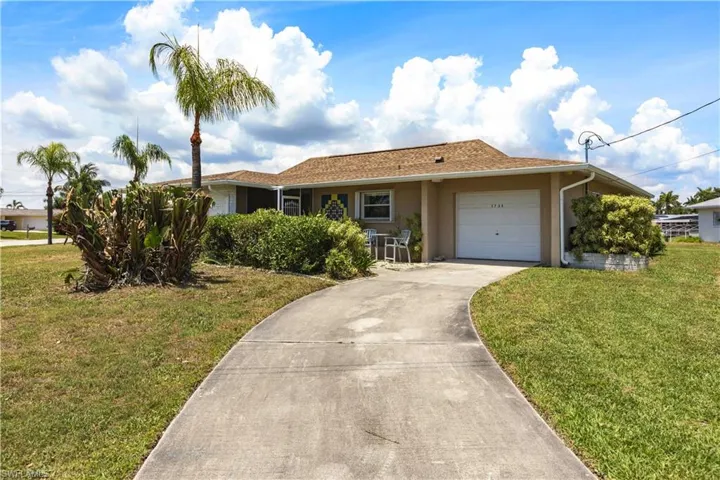 Ranch-style home featuring a garage, a front lawn, concrete driveway, and stucco siding