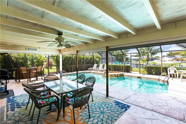 View of swimming pool with outdoor dining space, a patio area, a pool with connected hot tub, a ceiling fan, and glass enclosure