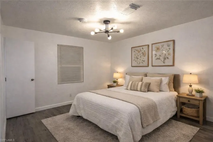 Bedroom featuring dark wood-style flooring, a textured ceiling, and hanging lights