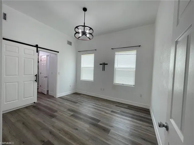 Unfurnished bedroom featuring a barn door and wood finished floors