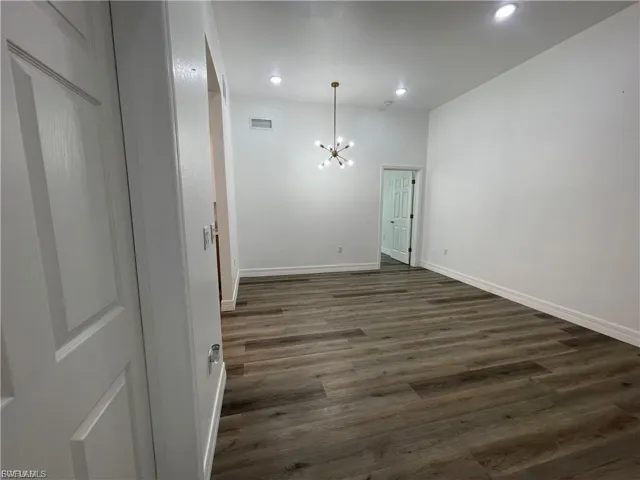 Unfurnished room featuring dark wood-style floors, a chandelier, and recessed lighting