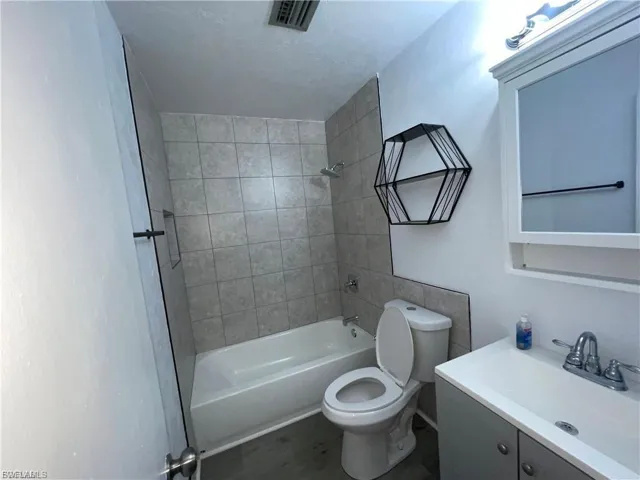 Full bath featuring vanity, shower / bath combination, and wood finished floors