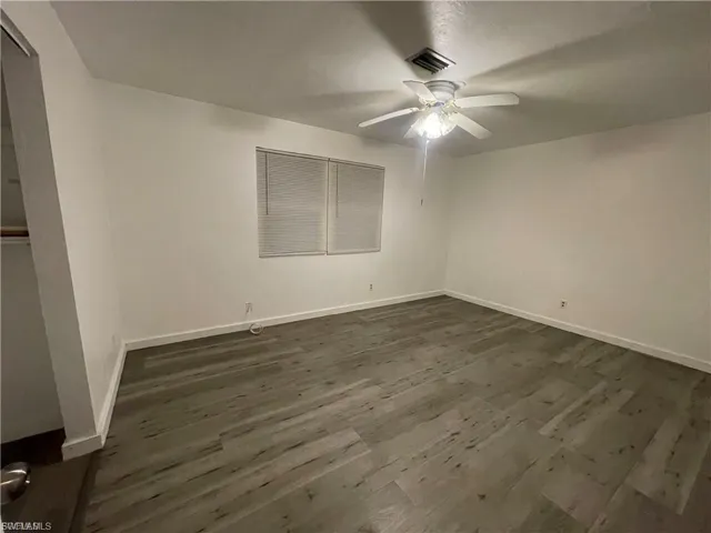 Unfurnished bedroom featuring dark wood-type flooring and ceiling fan