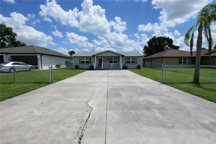 Ranch-style house featuring driveway, a porch, and a gate