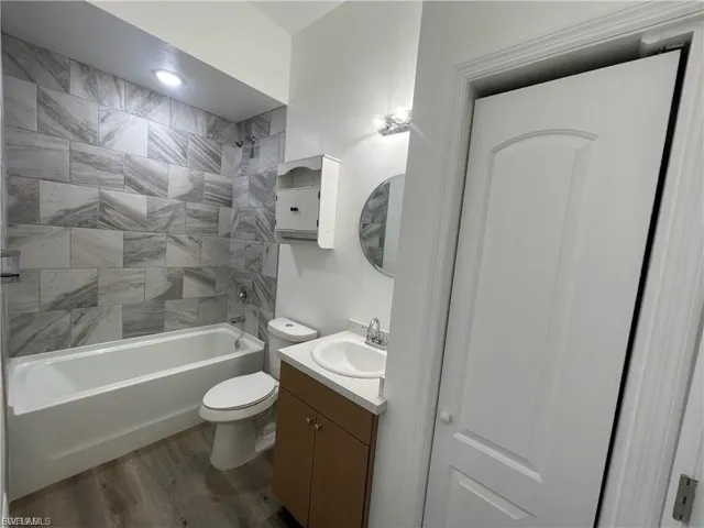 Full bathroom with vanity, shower / bath combination, and wood finished floors