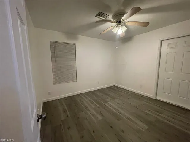 Unfurnished room featuring dark wood-style floors and a ceiling fan