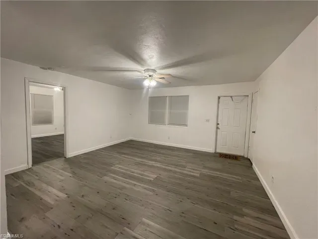Unfurnished bedroom featuring dark wood-style flooring, ceiling fan, and connected bathroom