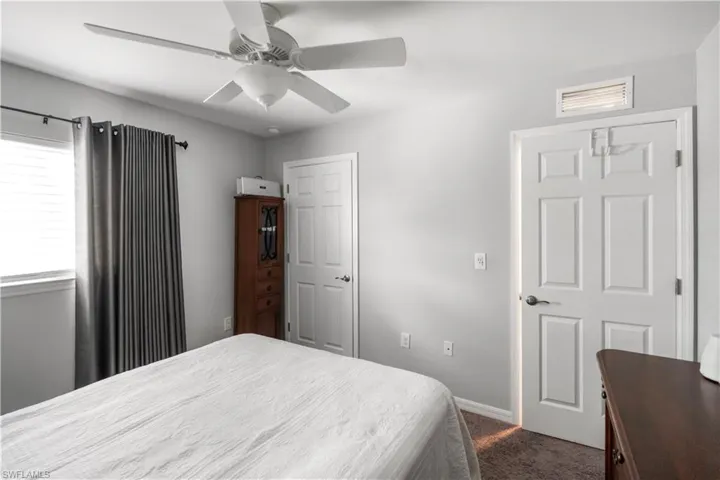 Interior space featuring a white ceiling fan with light fixture, light gray walls, and textured carpeting