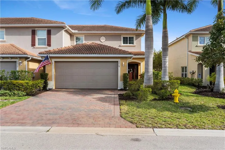 Two-story residence featuring a terracotta-style tile roof and a paver driveway