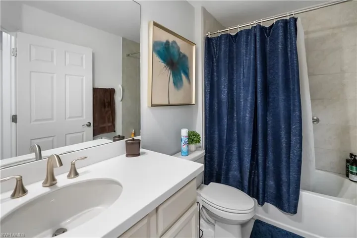 Bathroom featuring a white vanity with an integrated sink, brushed nickel faucet, full-width wall mirror, and a white toilet